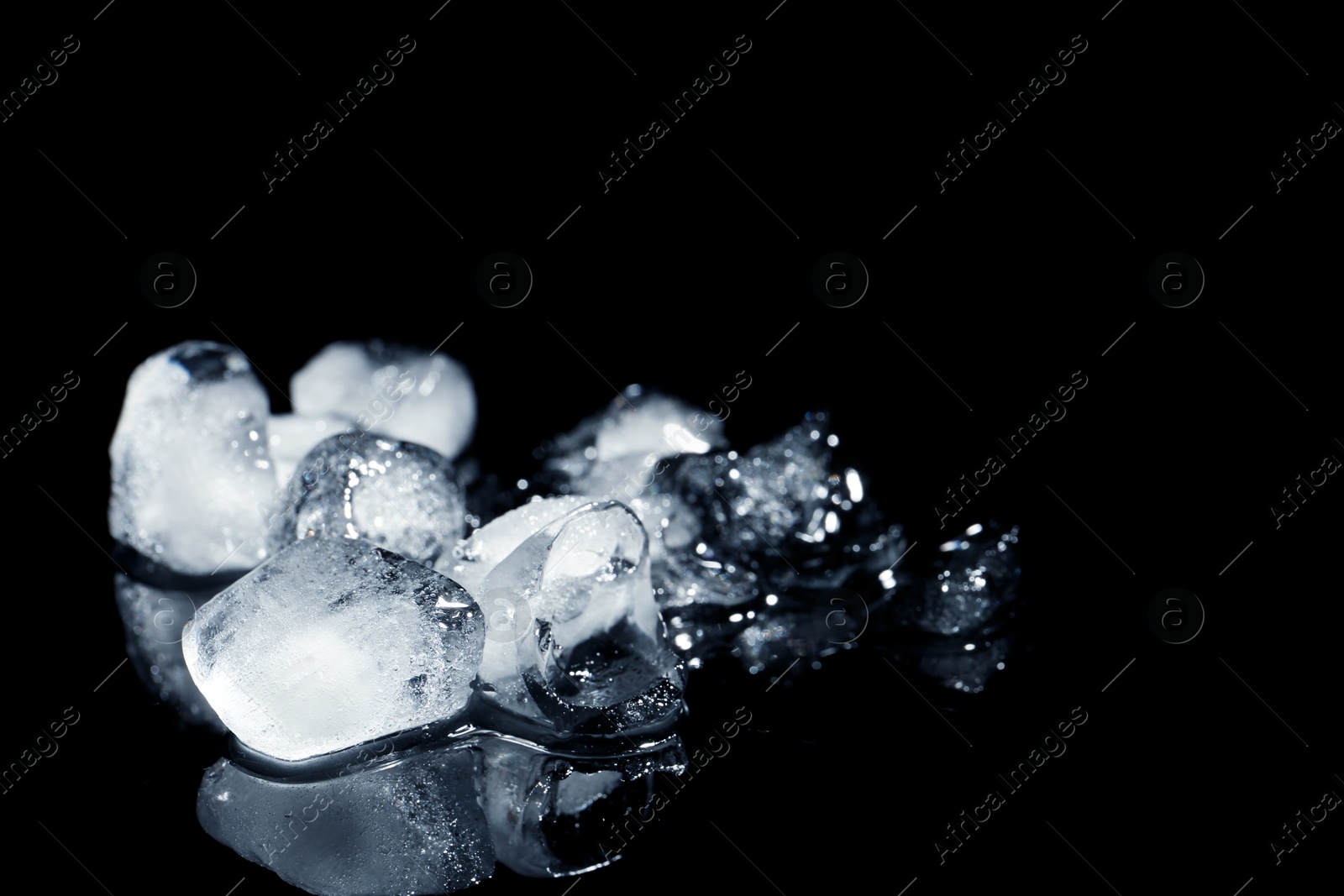 Photo of Melting ice cubes on black background. Space for text