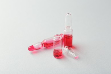 Photo of Glass ampoules with liquid on white background