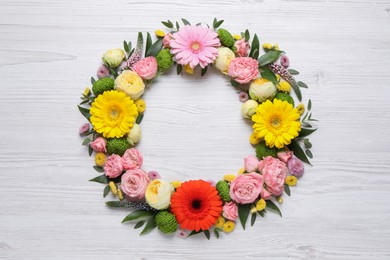 Photo of Wreath made of beautiful flowers and green leaves on white wooden background, flat lay. Space for text