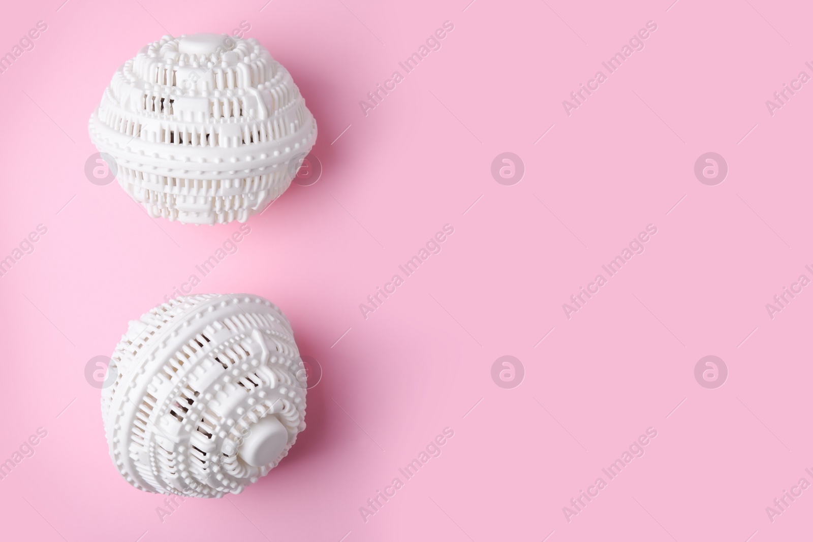 Photo of Laundry dryer balls on pink background, flat lay. Space for text