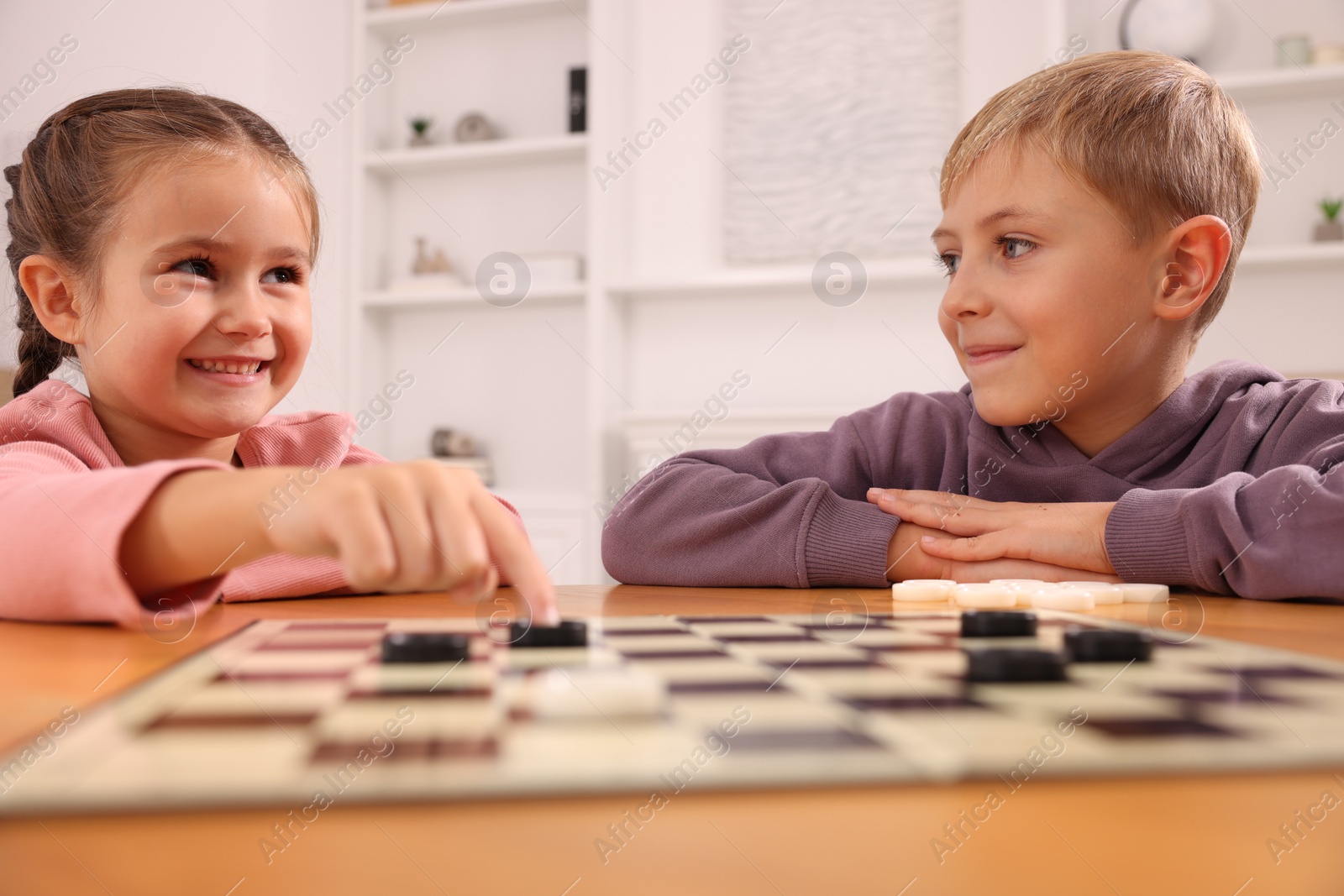 Photo of Children playing checkers at table in room