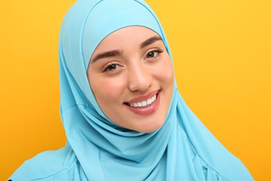 Portrait of Muslim woman in hijab on orange background