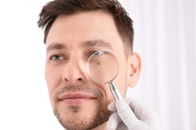 Dermatologist examining patient with magnifying glass in clinic