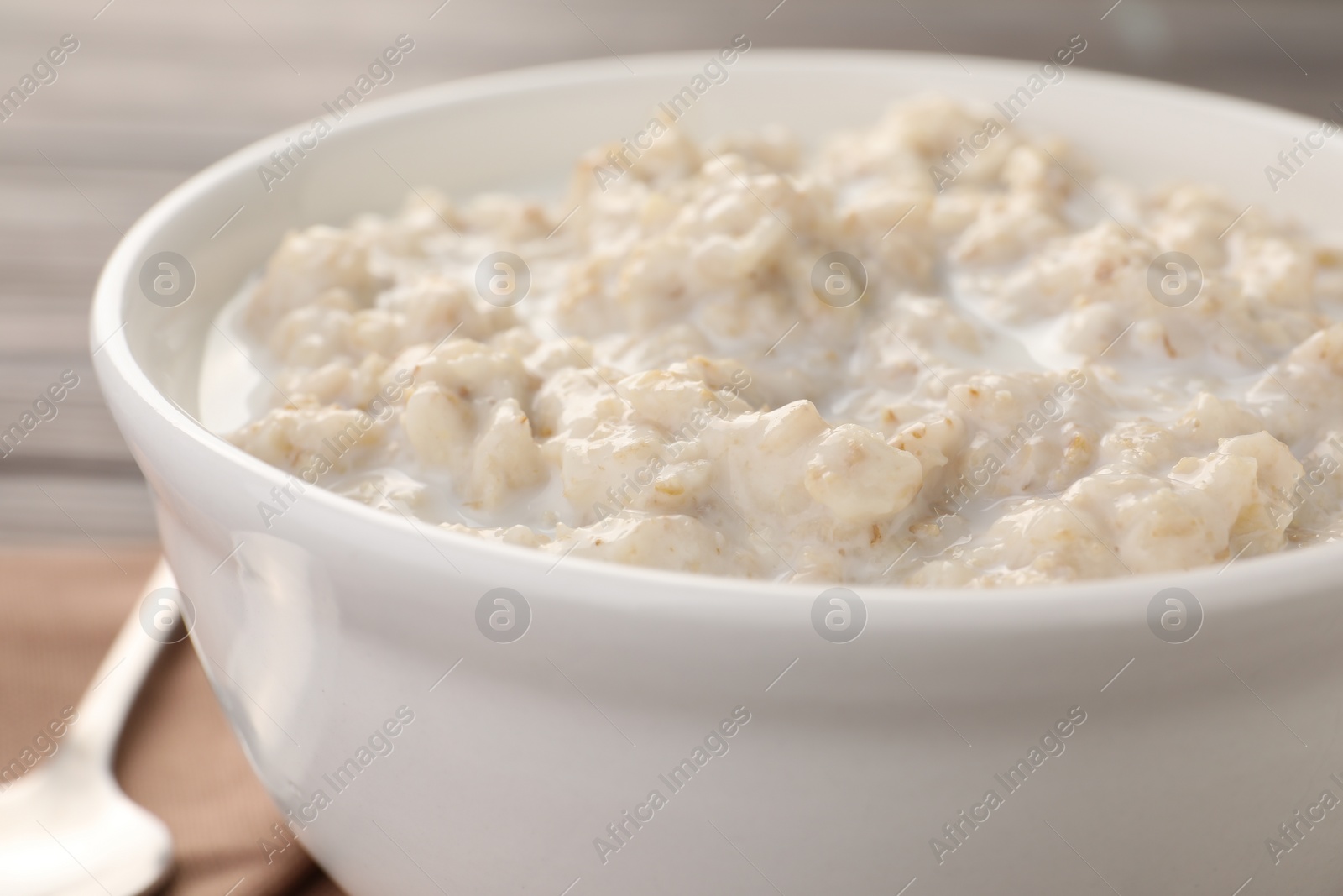 Photo of Tasty boiled oatmeal in bowl on table, closeup