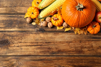 Photo of Flat lay composition with vegetables, nuts and autumn leaves on wooden table, space for text. Thanksgiving Day