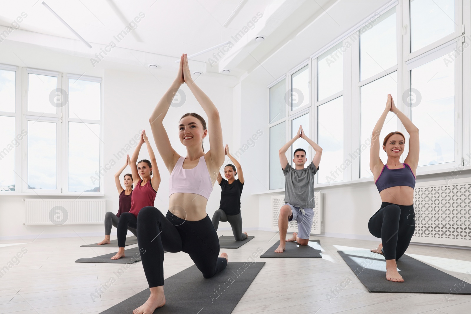 Photo of Group of people practicing yoga on mats indoors, low angle view