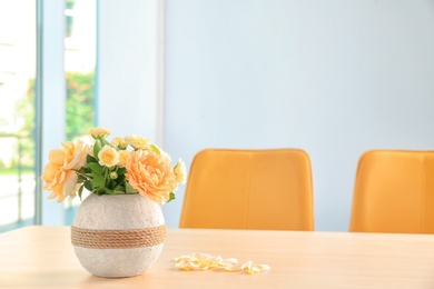 Vase with blooming flowers on table indoors