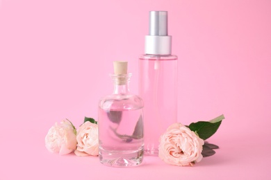 Photo of Bottles of essential oil and roses on pink background