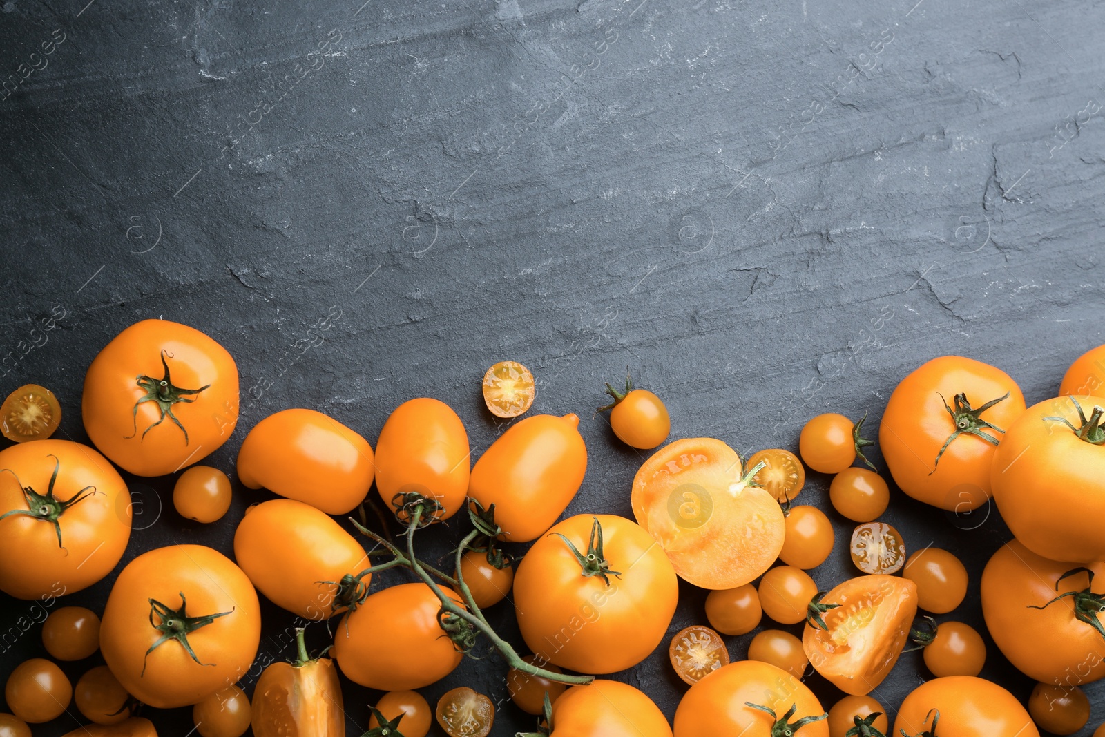 Photo of Ripe yellow tomatoes on black table, flat lay. Space for text