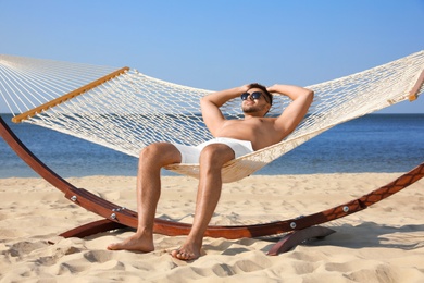 Photo of Young man relaxing in hammock on beach