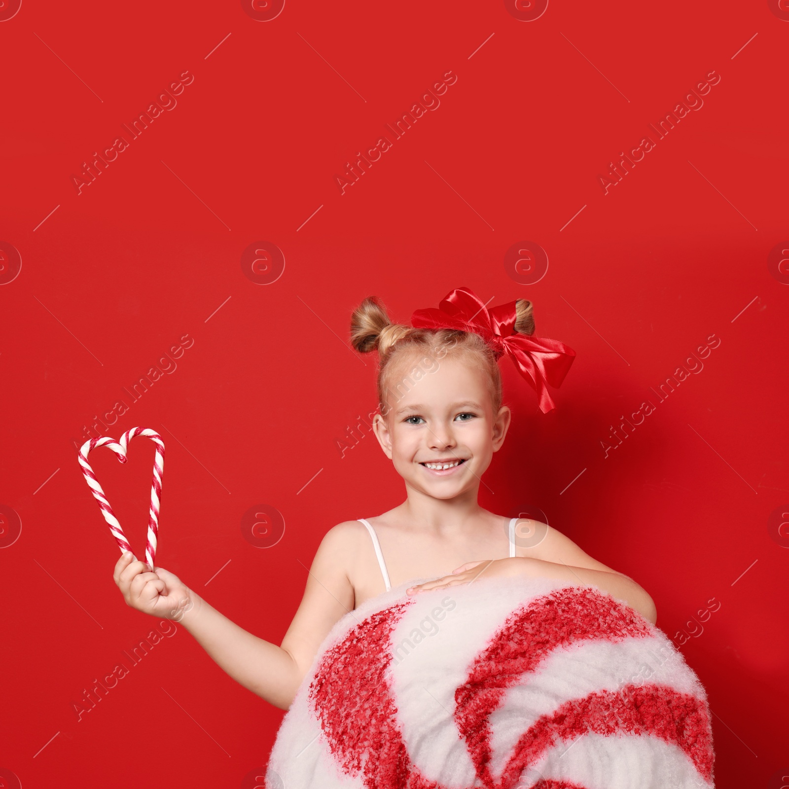 Image of Cute little girl dressed as candy with sweets on red background. Christmas suit