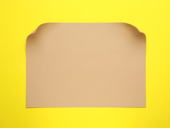 Photo of Sheet of brown paper on yellow background, top view