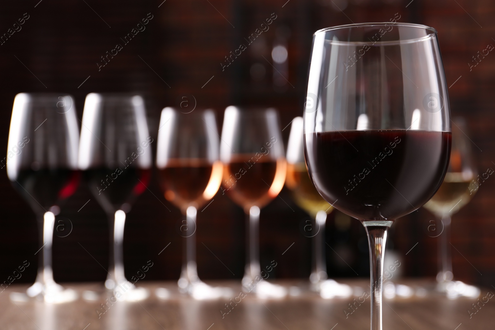 Photo of Different tasty wines in glasses against blurred background
