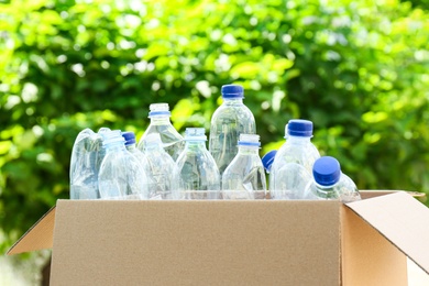 Photo of Cardboard box with used plastic bottles outdoors. Recycle concept