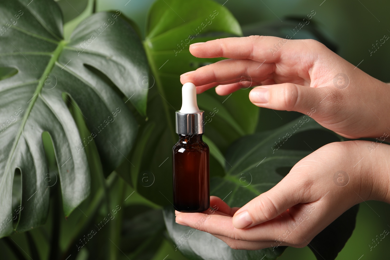 Photo of Woman with bottle of cosmetic serum on green background, closeup