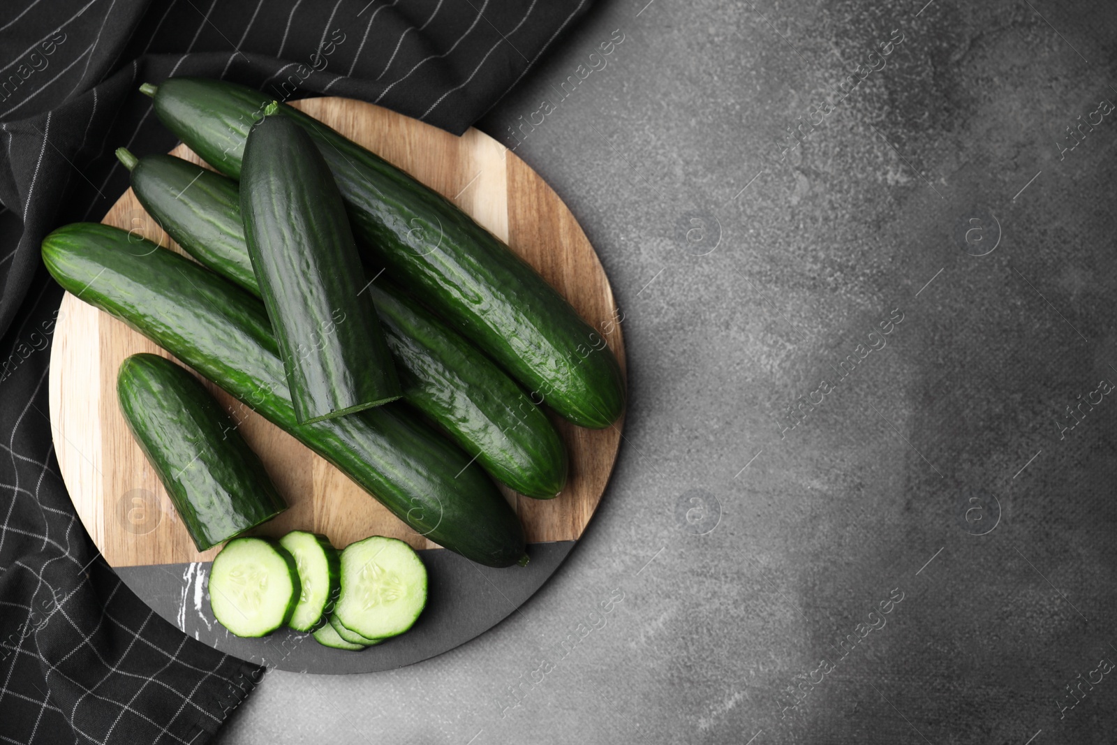 Photo of Fresh cucumbers on grey textured table, top view. Space for text