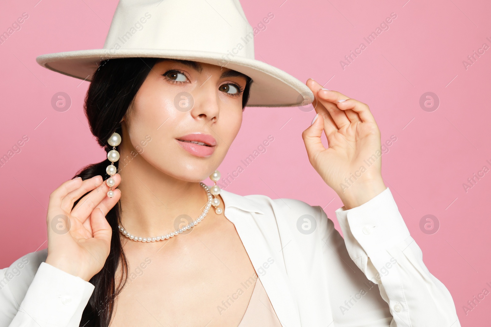 Photo of Young woman wearing elegant pearl jewelry on pink background