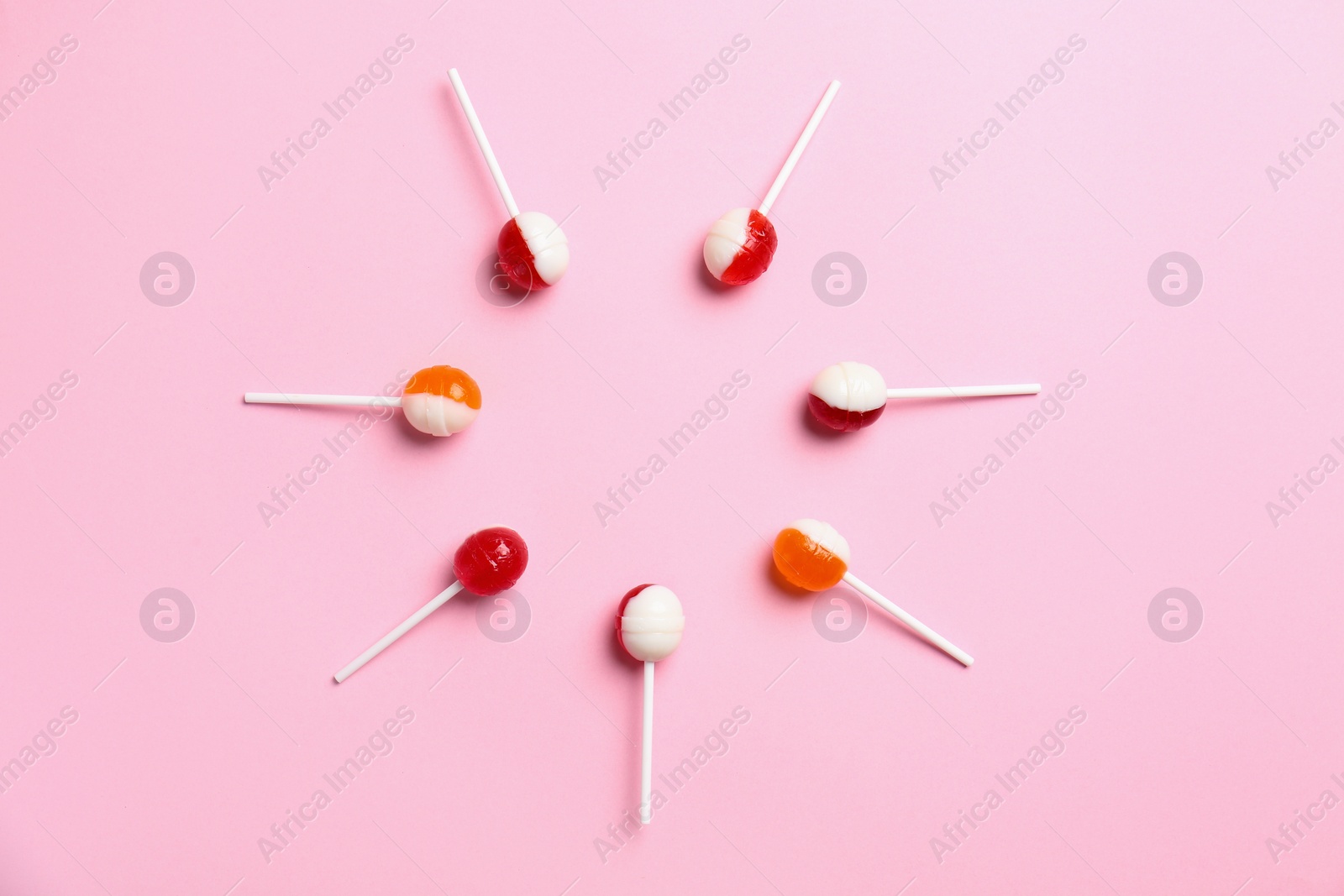 Photo of Flat lay composition with delicious lollipop candies on pink background. Space for text