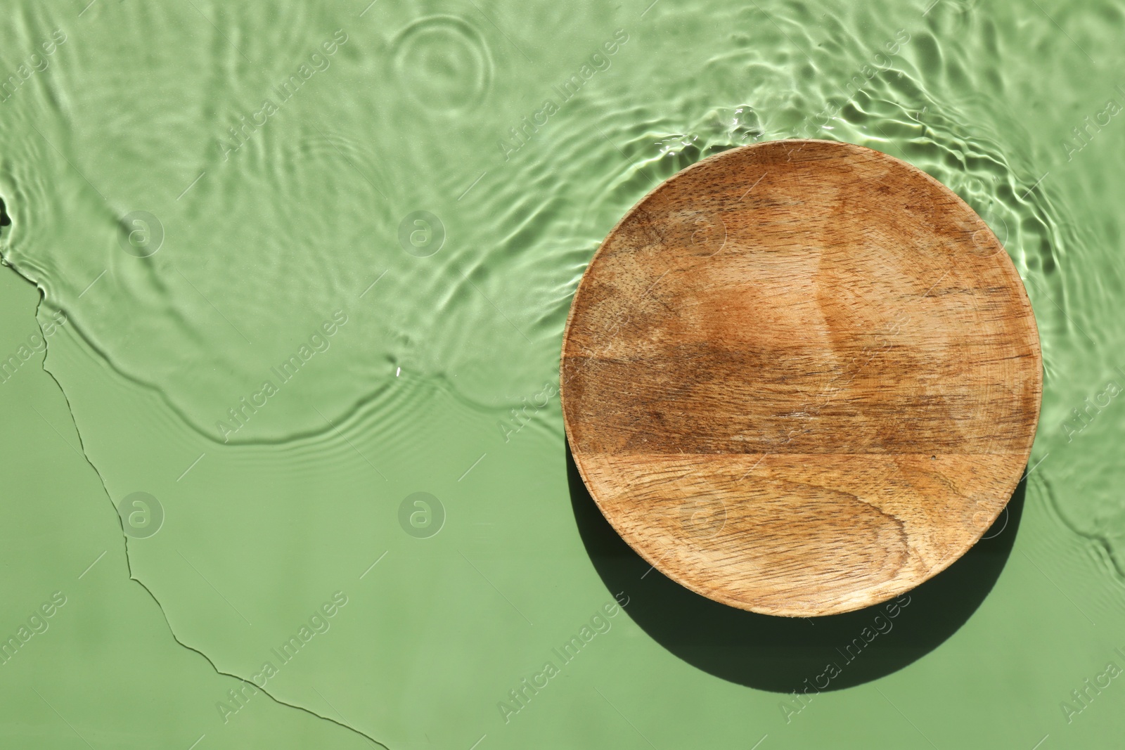 Photo of Presentation of product. Wooden podium in water on green background, top view. Space for text