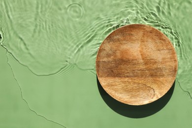 Photo of Presentation of product. Wooden podium in water on green background, top view. Space for text