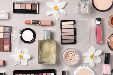 Photo of Flat lay composition with different makeup products and beautiful spring flowers on grey background