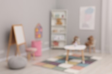 Photo of Blurred view of child`s playroom with different toys and modern furniture. Stylish kindergarten interior