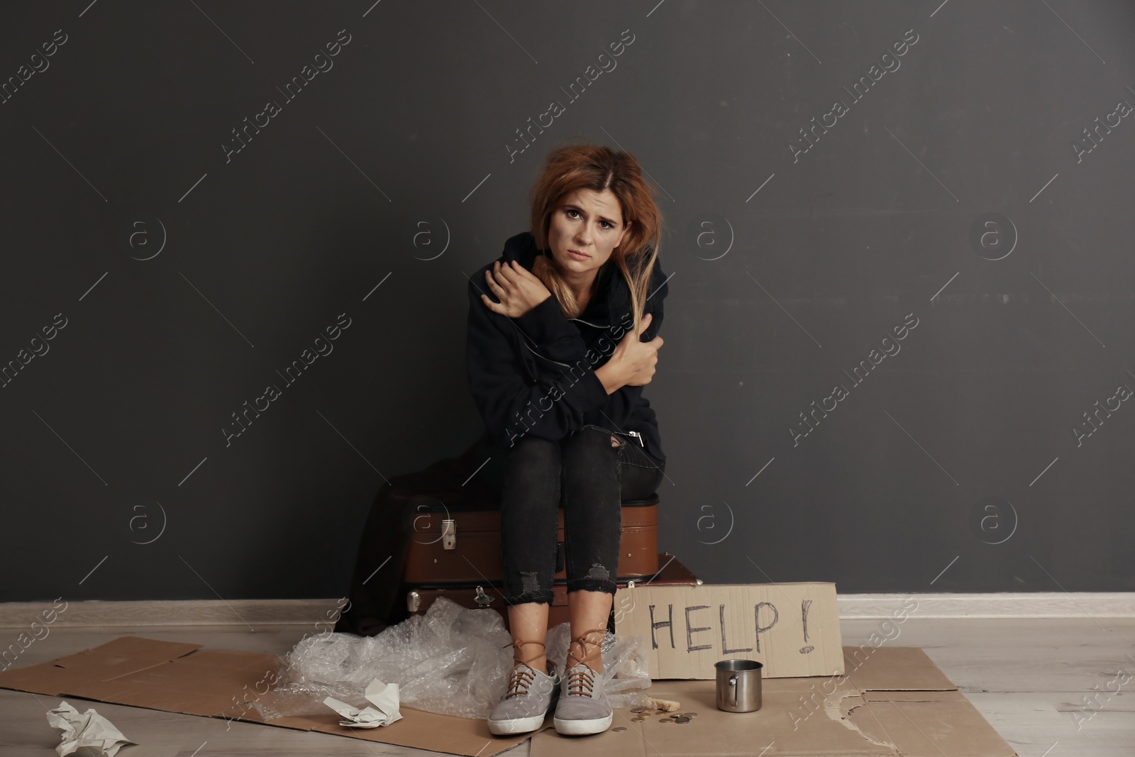 Photo of Poor homeless woman asking for help near dark wall