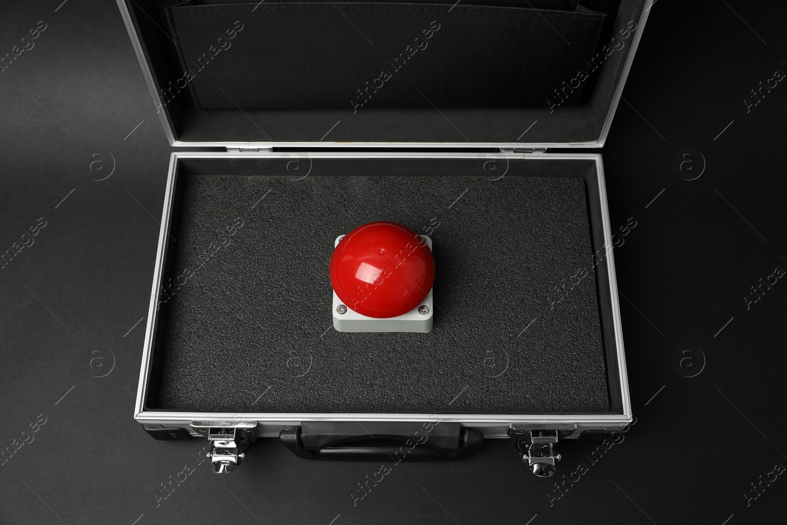 Photo of Red button of nuclear weapon in suitcase on black background, above view. War concept