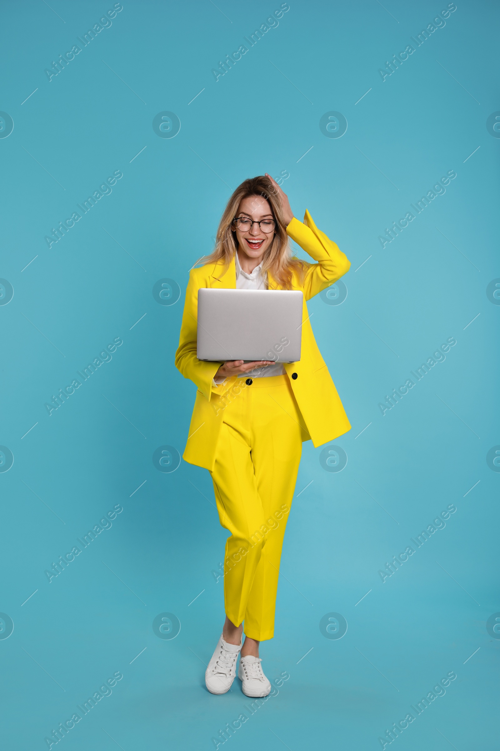 Photo of Young woman with modern laptop on light blue background