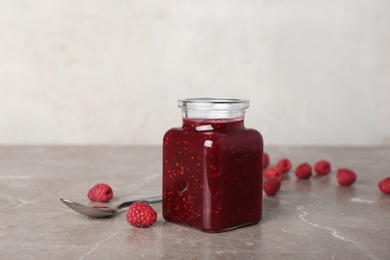 Jar with delicious raspberry jam on table