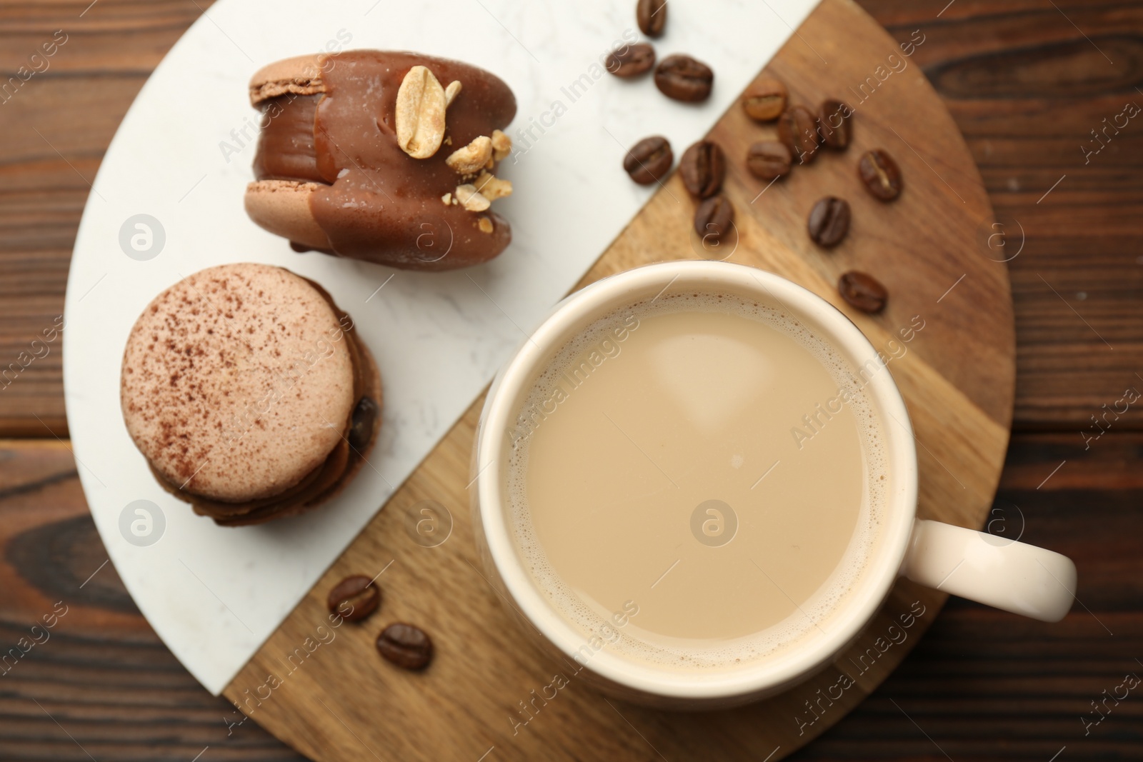 Photo of Cup of coffee and delicious macarons on wooden table, top view