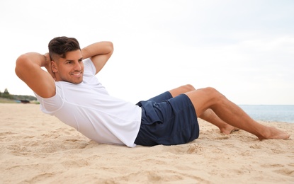 Photo of Muscular man doing exercise on beach. Body training