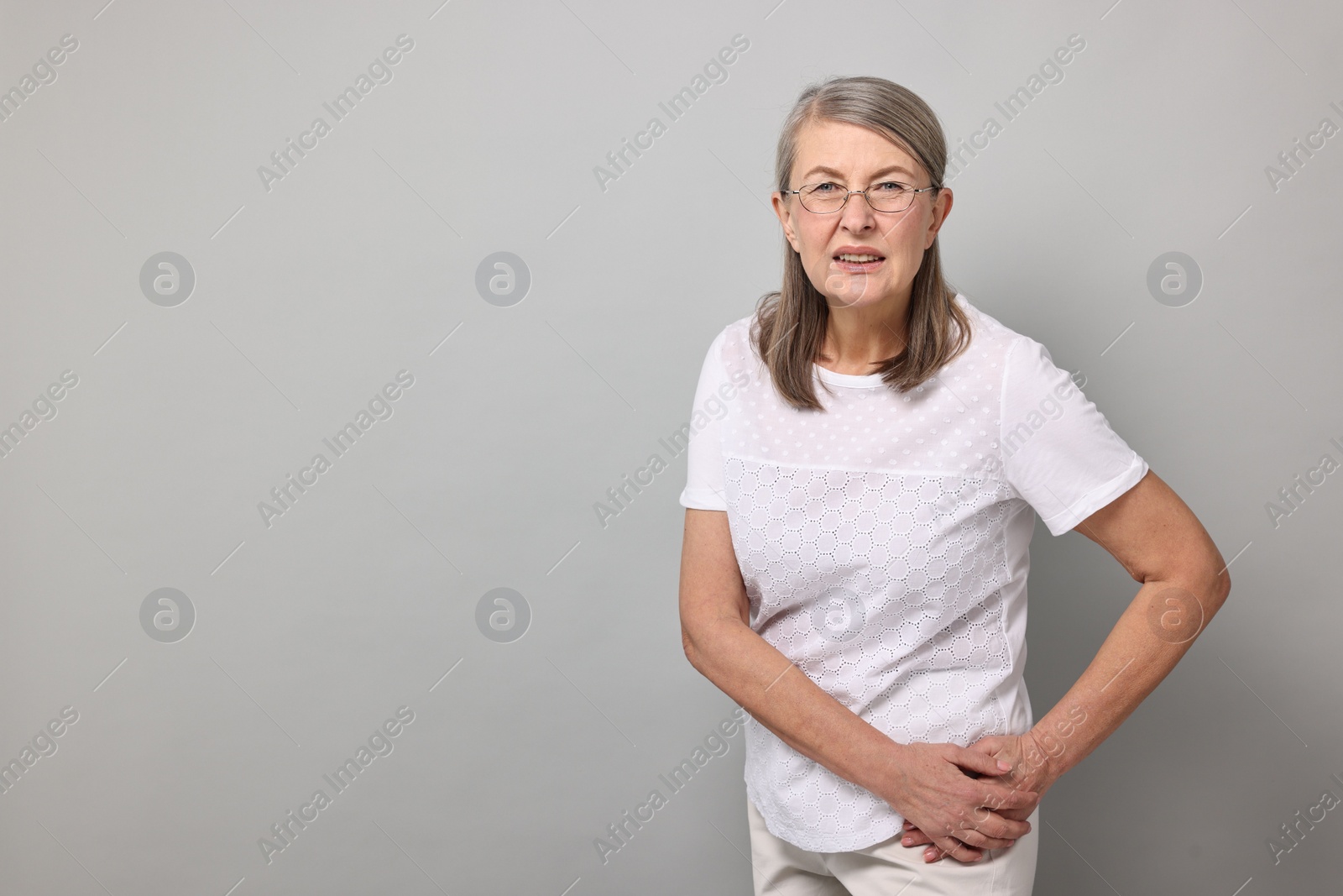 Photo of Arthritis symptoms. Woman suffering from hip joint pain on gray background, space for text