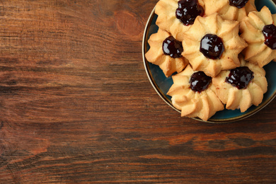Tasty shortbread cookies with jam on wooden table, top view. Space for text
