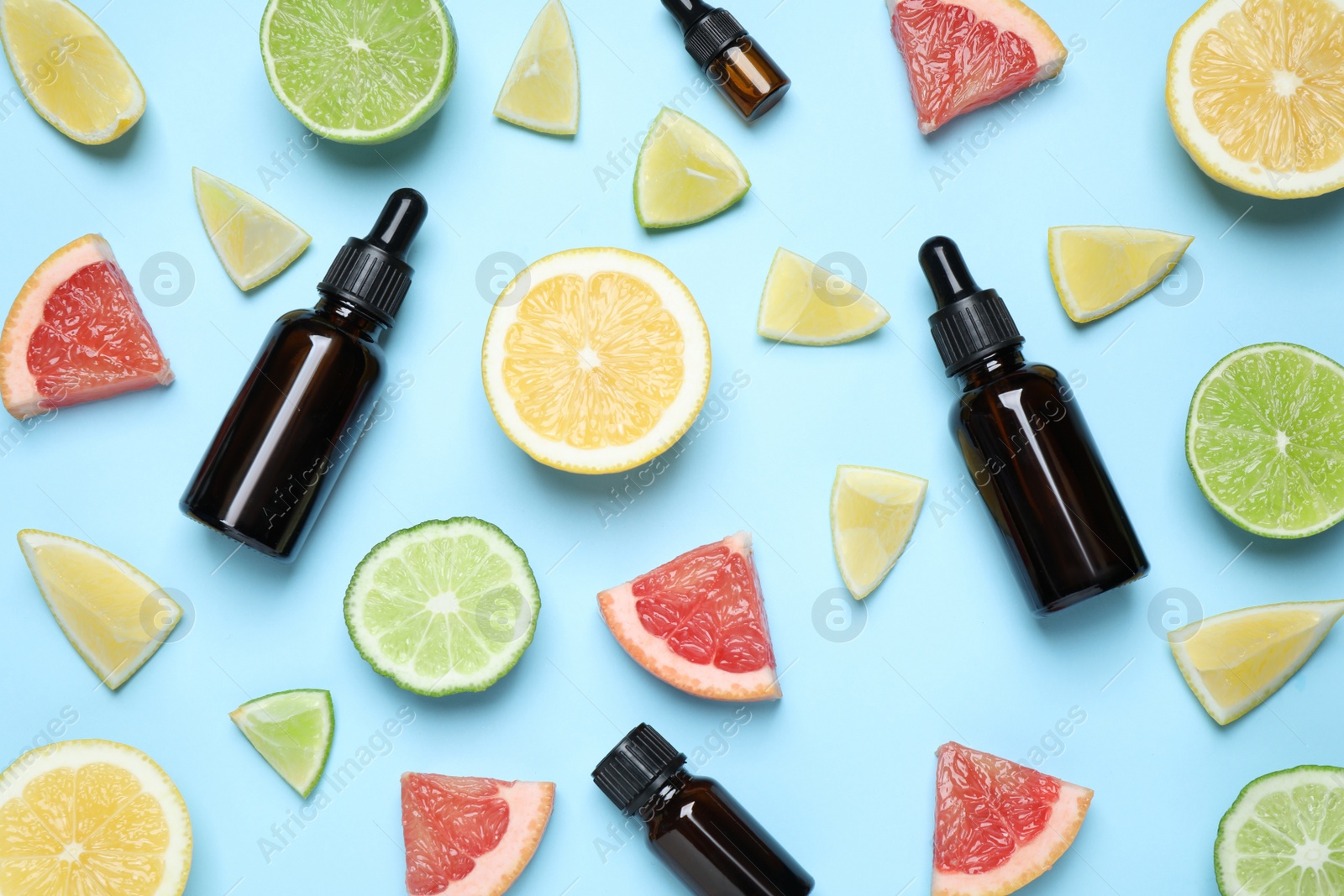 Photo of Flat lay composition with bottles of citrus essential oil on light blue background