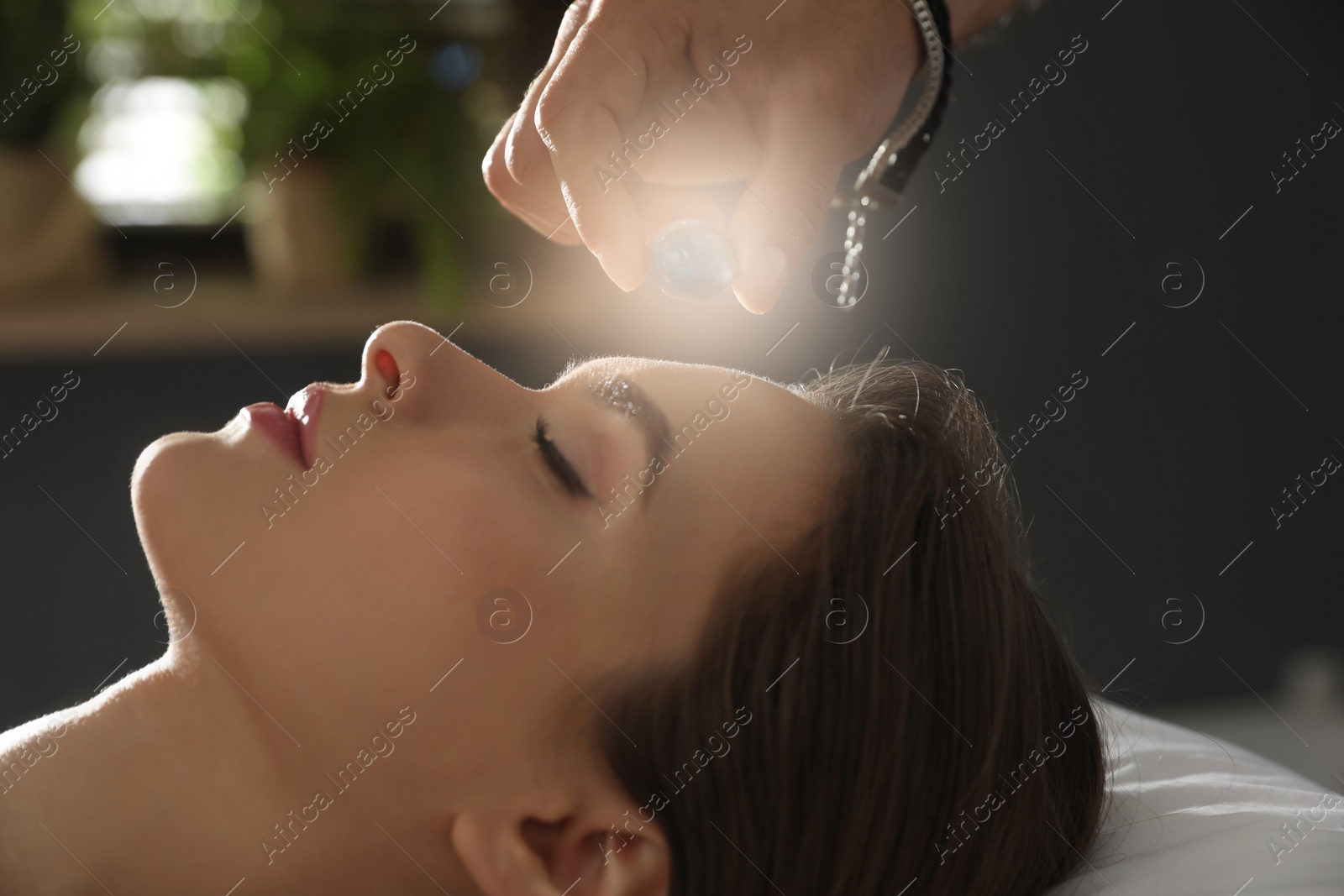 Photo of Young woman during crystal healing session in therapy room