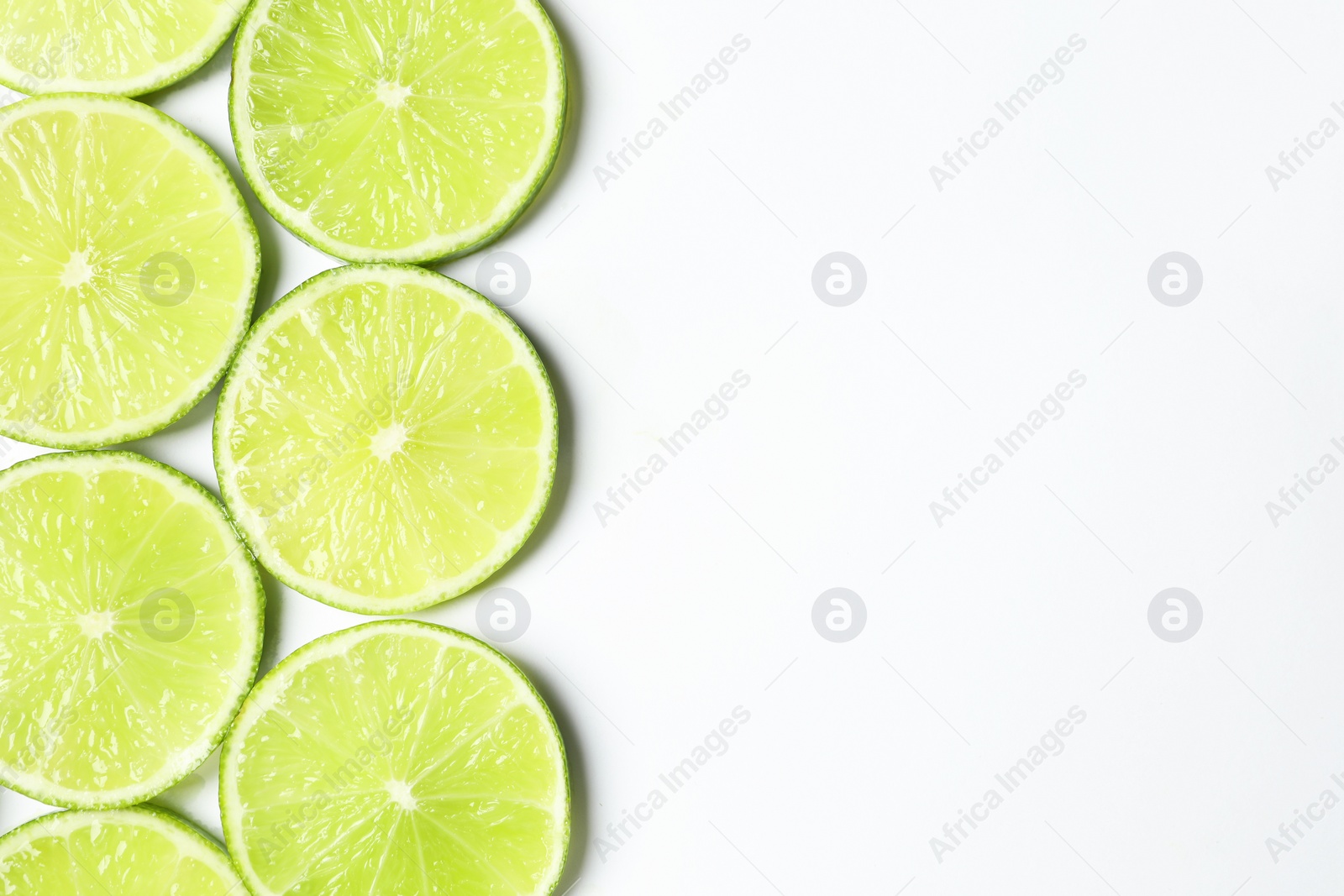 Photo of Fresh juicy lime slices on white background, flat lay. Space for text