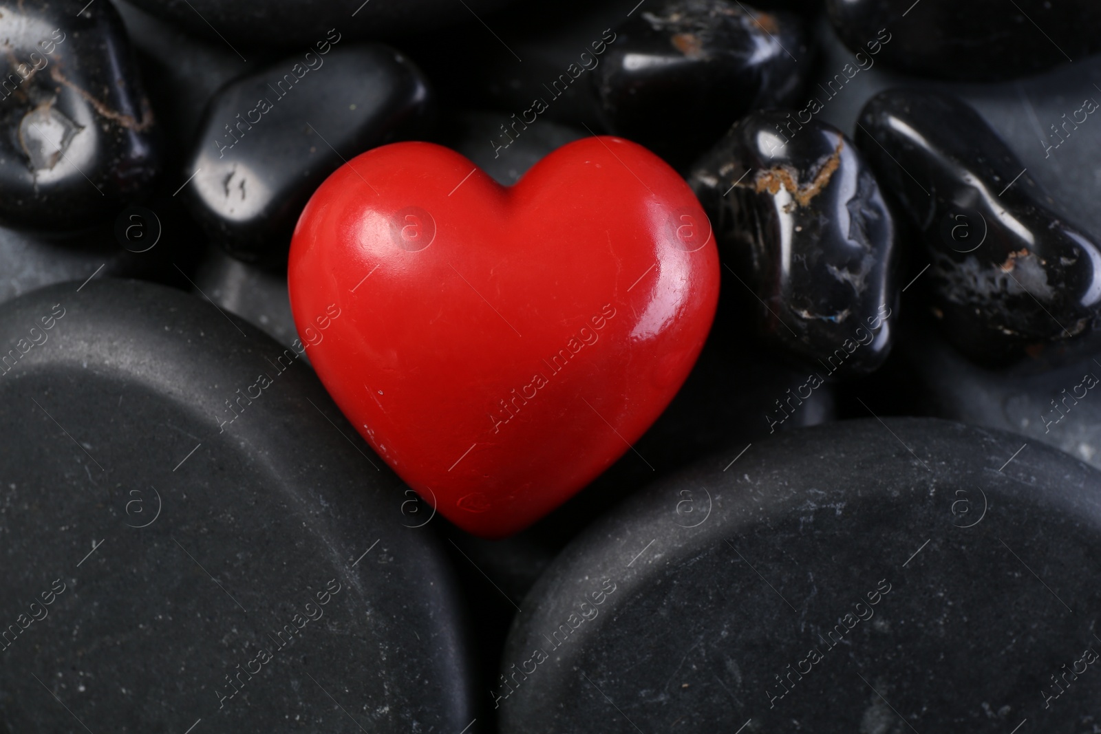 Photo of Red decorative heart on pebble stones, above view