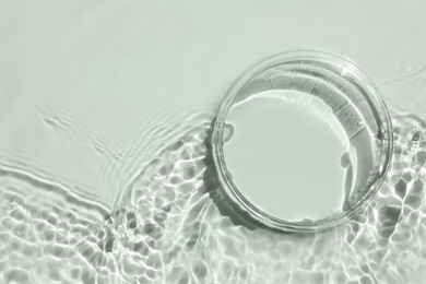 Photo of Stylish presentation for product. Glass podium in water on white background, top view. Space for text