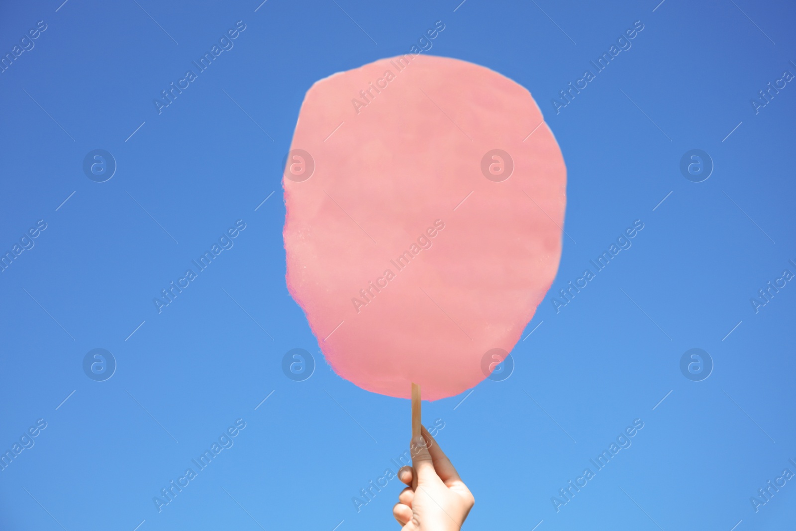 Photo of Woman holding white cotton candy against blue sky