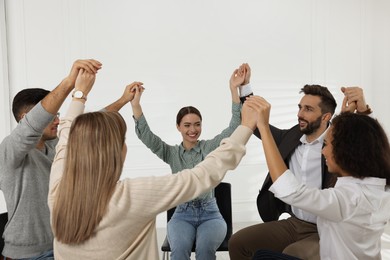 People holding hands at group therapy session indoors