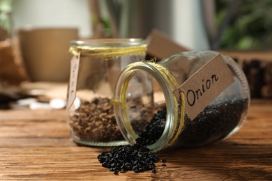 Glass jars with vegetable seeds on wooden table