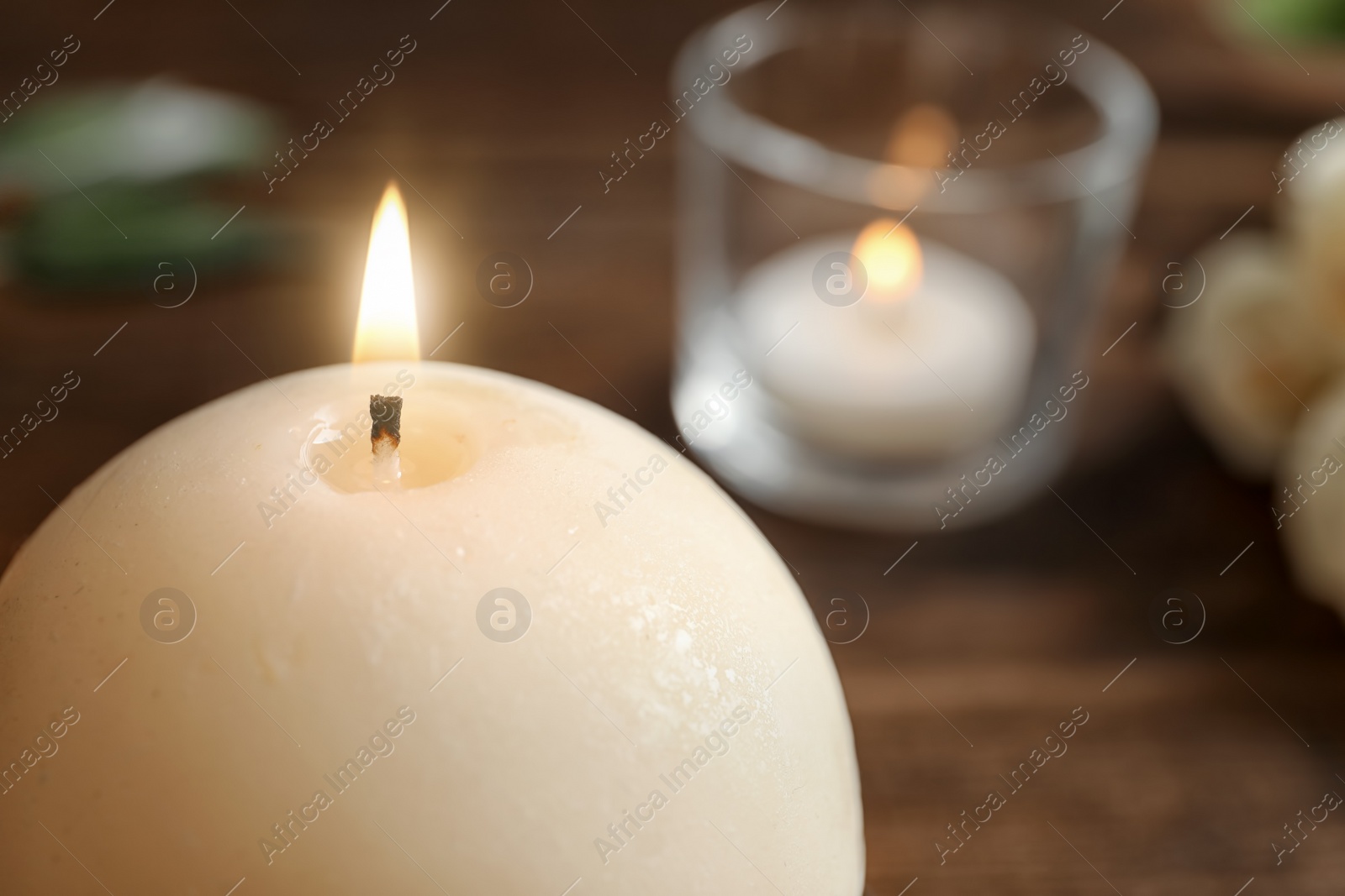 Photo of Round wax candle burning on table, closeup