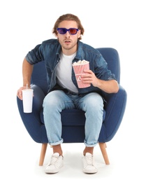 Emotional man with 3D glasses, popcorn and beverage sitting in armchair during cinema show on white background