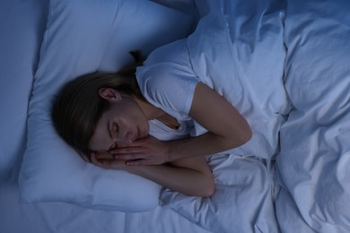 Woman sleeping in bed at night, above view