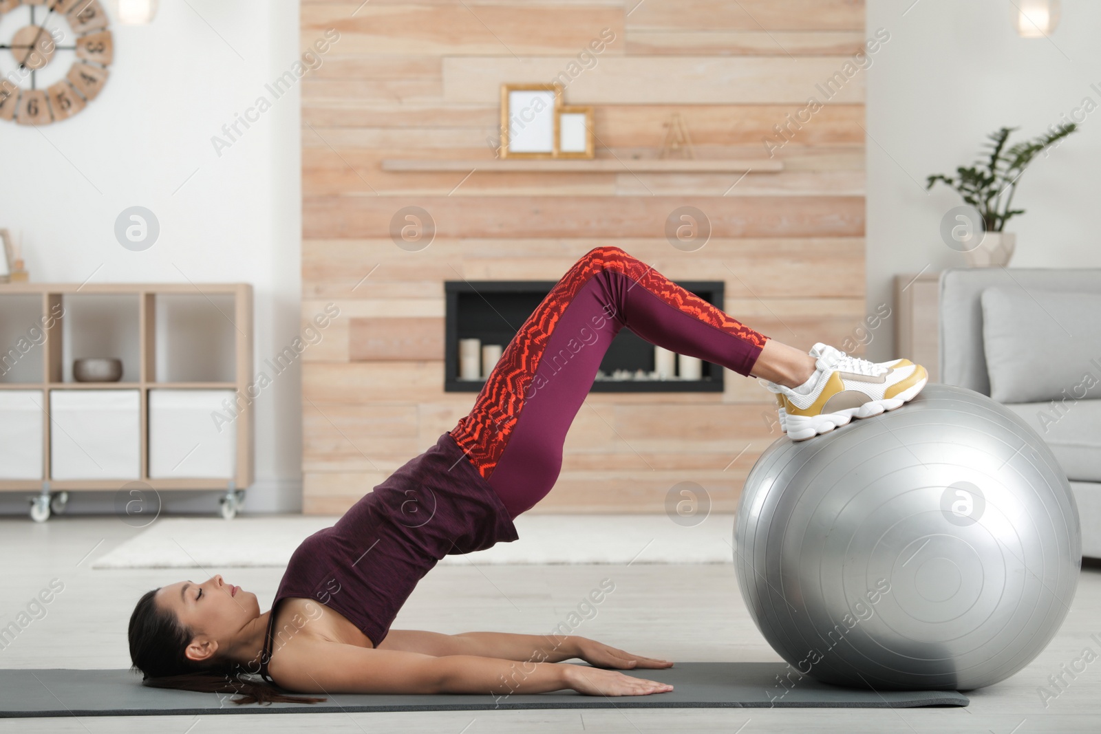 Photo of Young woman doing exercise with fitness ball at home. Space for text
