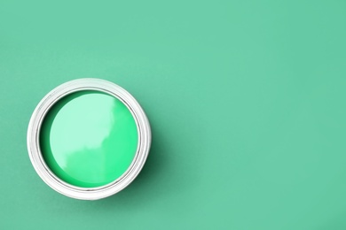 Open can of paint on green background, top view. Space for text