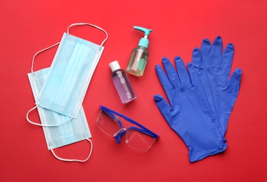 Photo of Flat lay composition with medical gloves, masks and hand sanitizers on red background