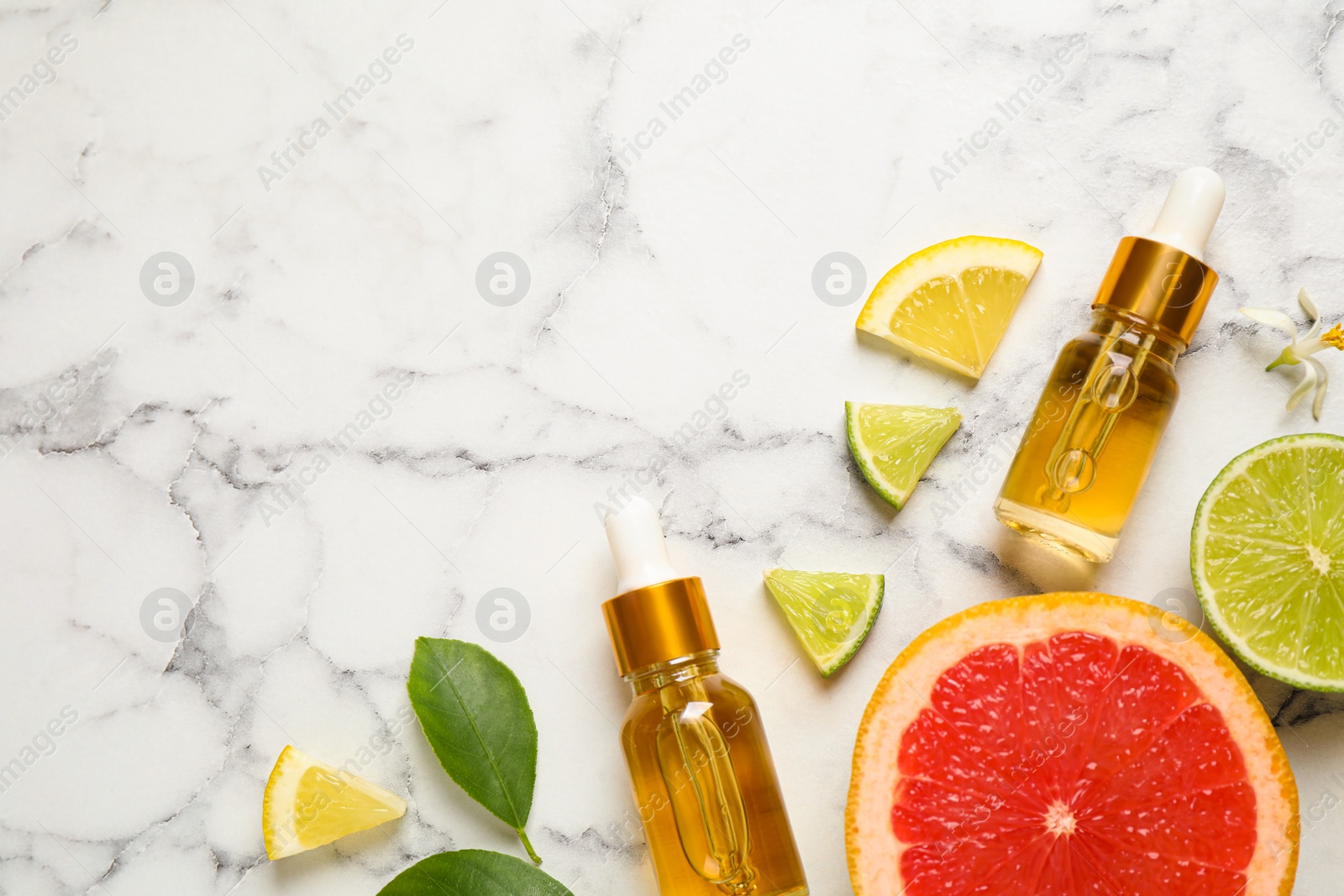 Photo of Flat lay composition with bottles of citrus essential oil on white marble background. Space for text