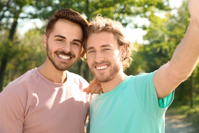 Photo of Portrait of happy gay couple smiling in park